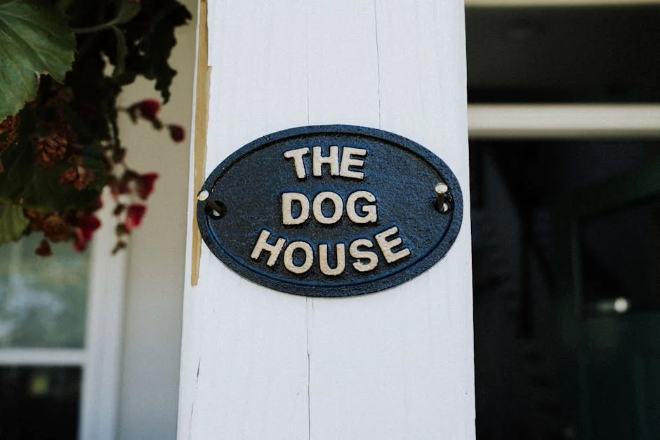 Close-up of a rustic 'The Dog House' sign on a white wooden post with foliage. - aesthetic pet names