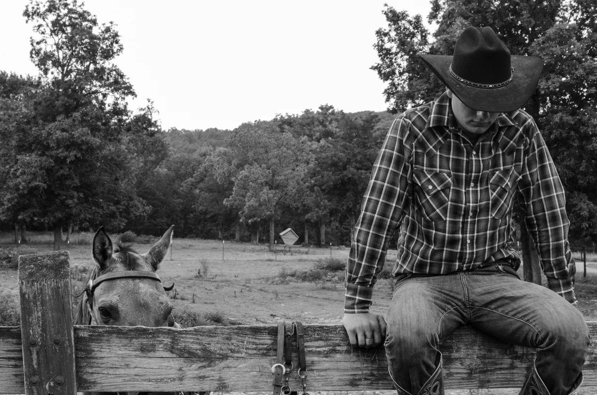 a man and a donkey by a fence - cowboy names for dogs