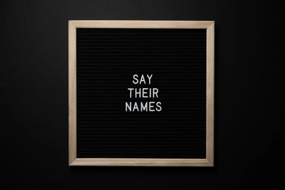 Top view composition of black framed photo with white text Say Their Names placed on black background - gothic pet names