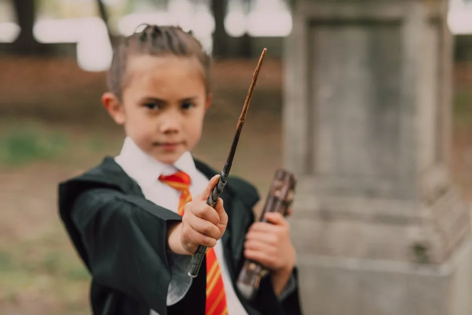 A young boy in a wizard costume holding a wand and book in an outdoor setting. - harry potter dog names