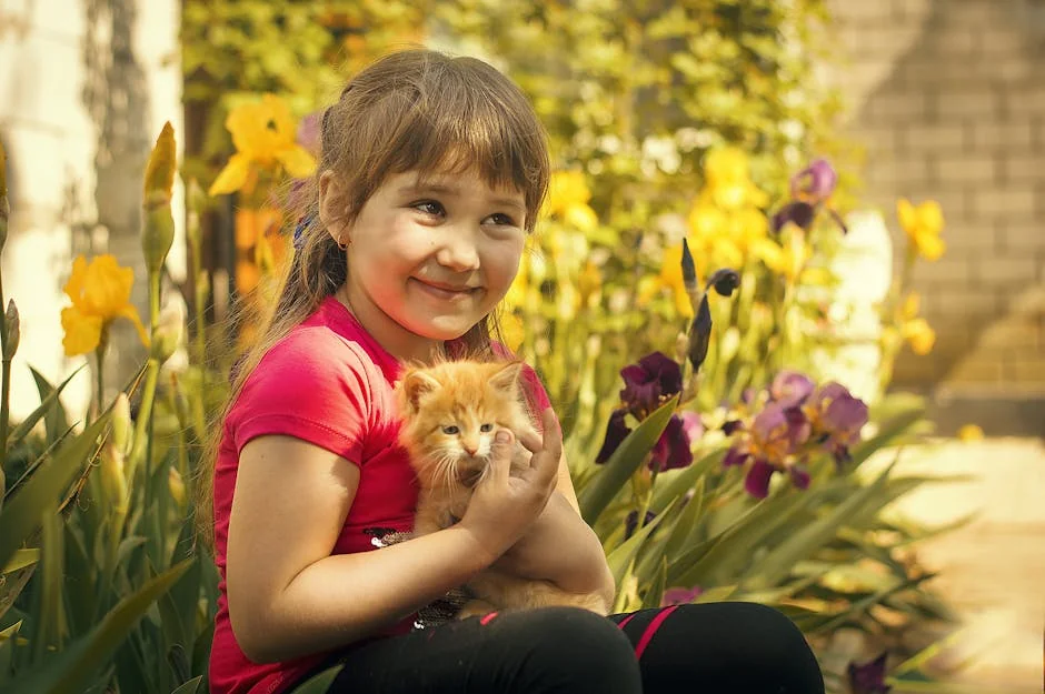 A happy girl holding a kitten surrounded by colorful irises in a garden. - nature inspired pet names for girls