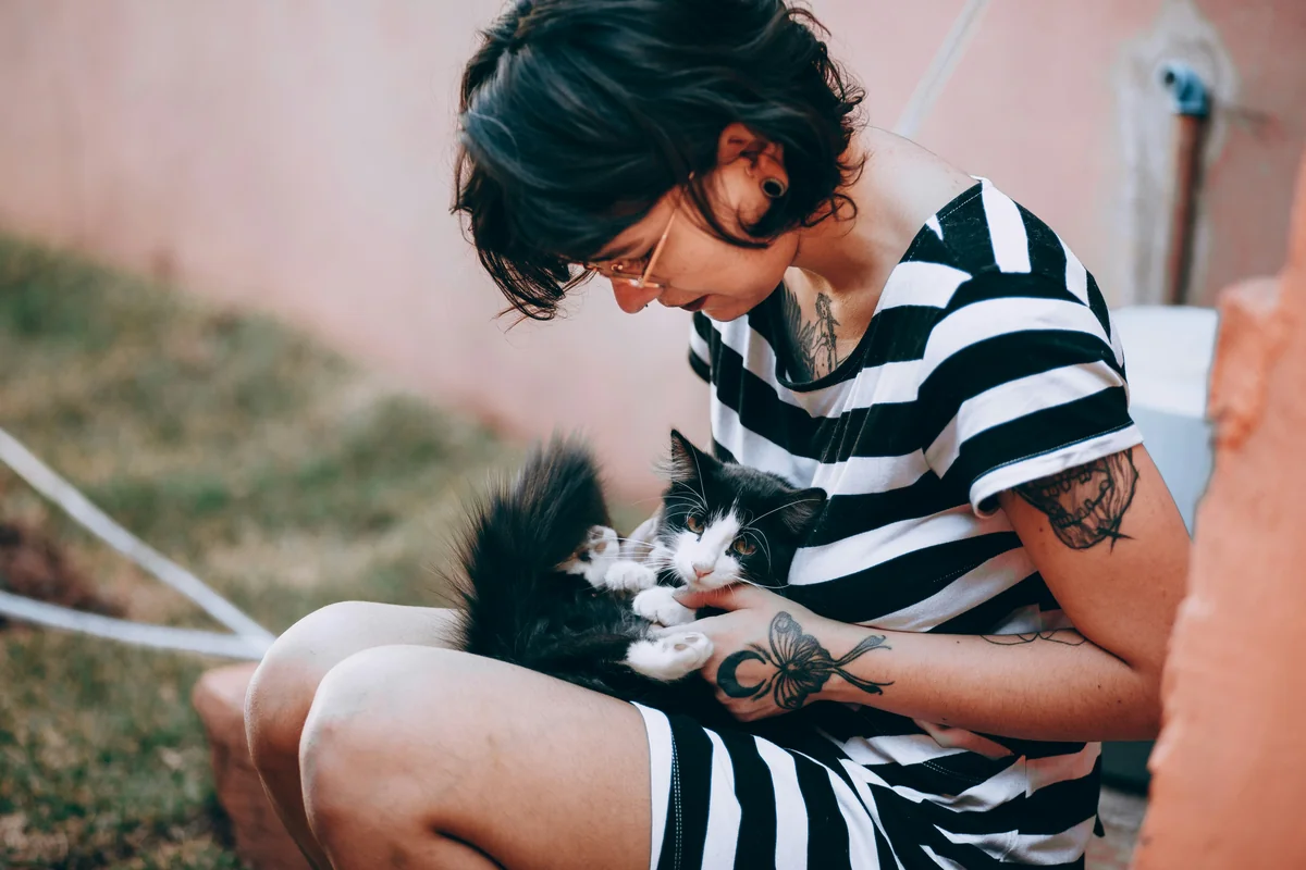 woman in black and white stripe shirt holding black and white cat - rare gender neutral pet names