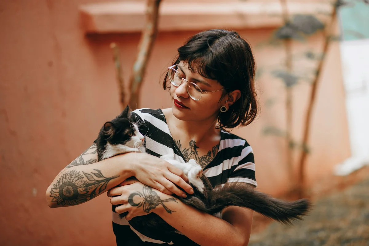 woman in black and white stripe shirt hugging white and black short coated dog - royal sounding names for female pets