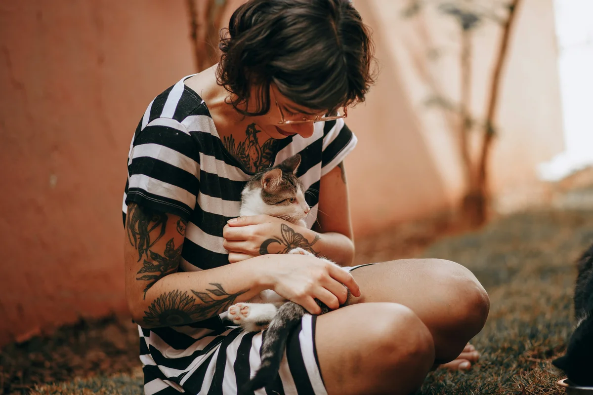 woman in black and white stripe shirt carrying white and brown cat - royal sounding names for female pets