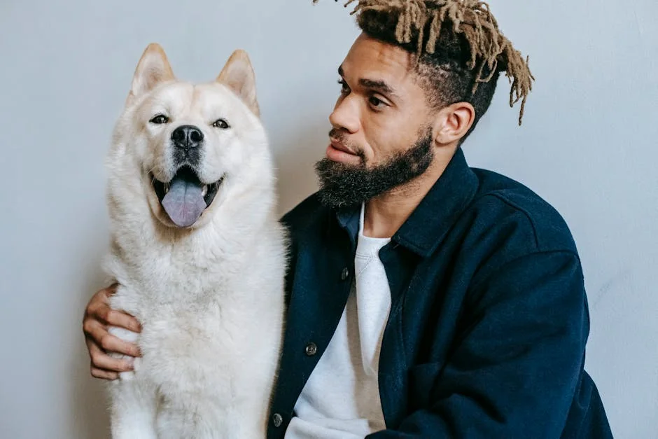 Crop African American male with dreadlocks in casual outfit with fluffy cute funny Akita Inu looking away on white background - unique male dog names with meaning