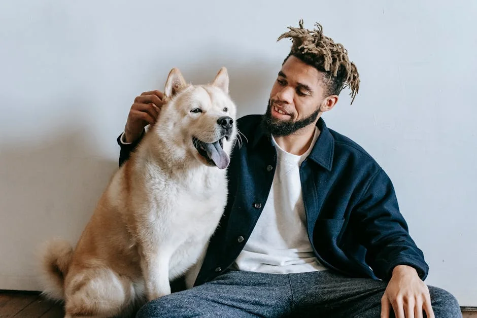 Caring African American male with dreadlocks patting fluffy cute funny Akita Inu dog with tongue out - unique male dog names with meaning