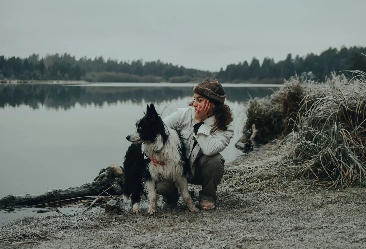 a woman sitting next to a dog on a beach - viking dog names